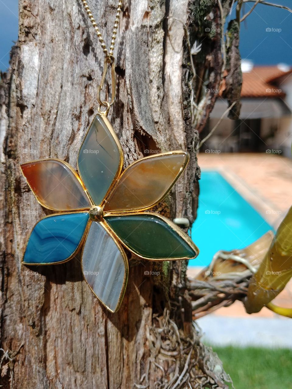 A  piece of jewelry,flower of different rocks, against an old trunk