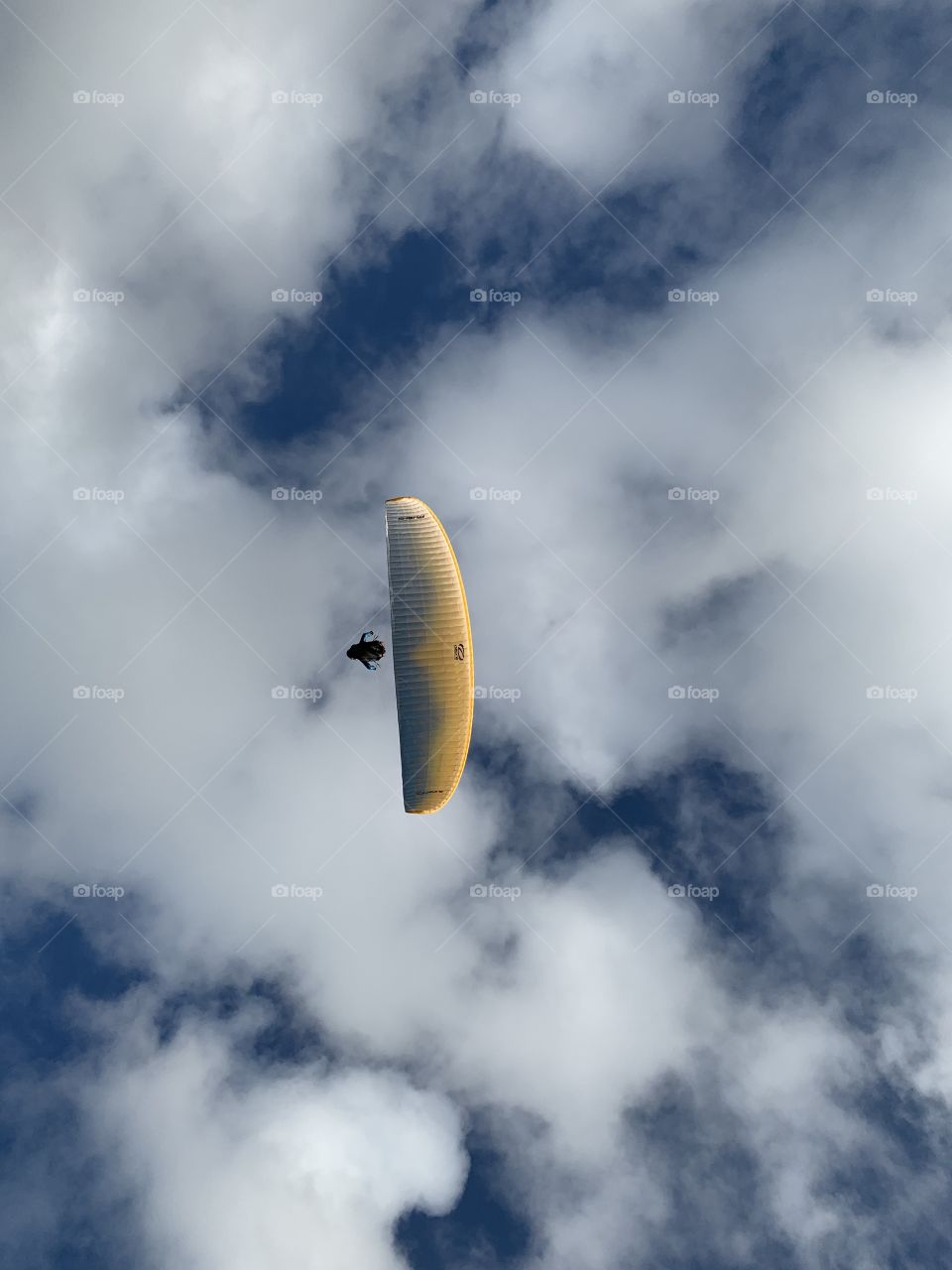 Paraglider overhead sails through the blue sky