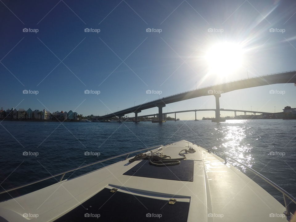 Boat traveling towards the sun Heading towards a bridge