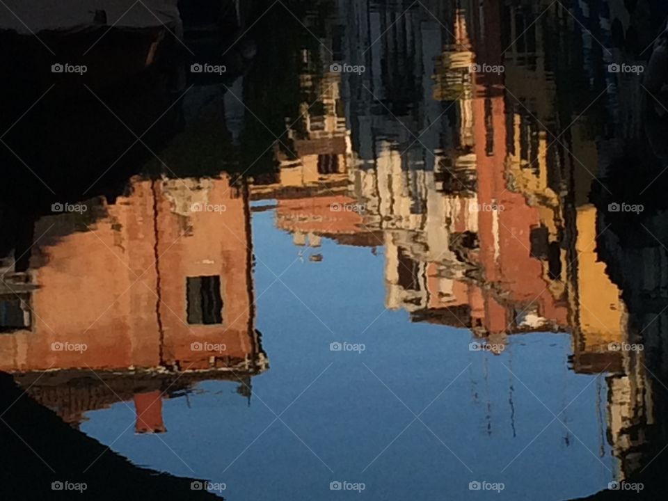 Venetian houses reflect in the water of a canal. 