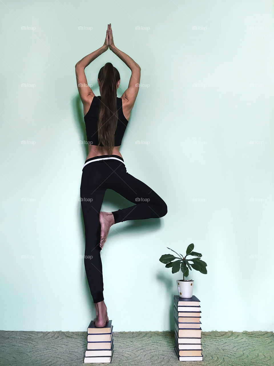 Young woman going yoga nearby growing plant