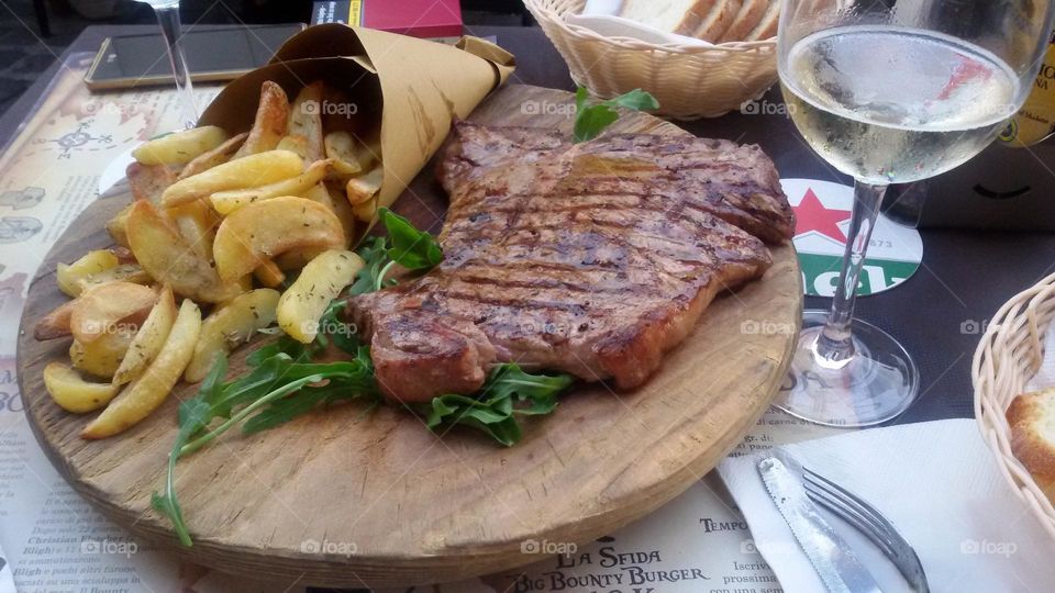 grilled steak and fries served on a wooden plate