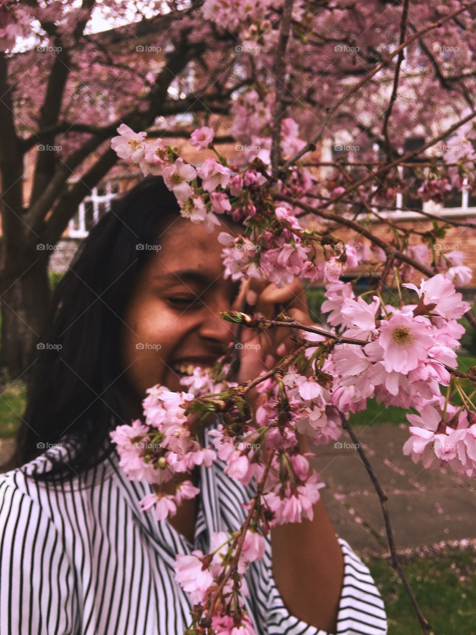 Model laughing behind cherry blossoms. 
