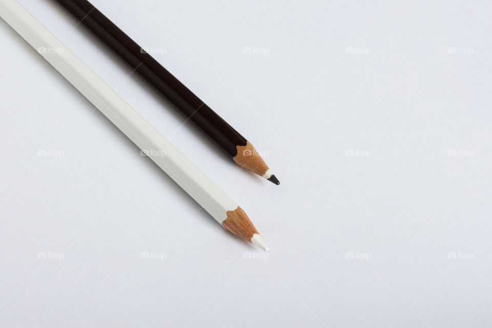 Two pencils, black and white on the white background