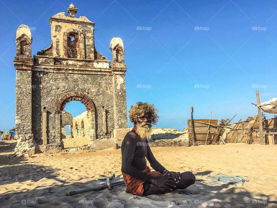 Portrait of an old man sitting in front of ruins