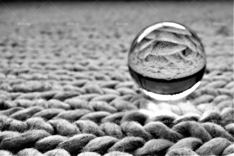 Crystal clear glass ball on knitted carpet in black and white