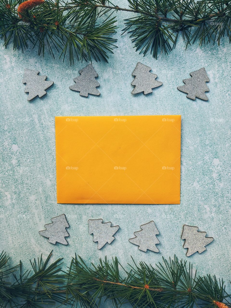 Christmas or New Year composition.  Paper yellow envelope with fir branches on a blue background. Flat lay. Top view.