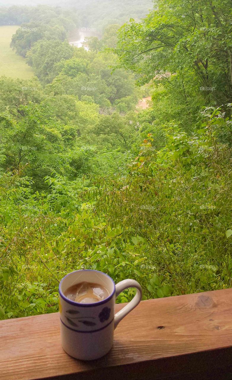 A coffee mug on a deck overlooking trees