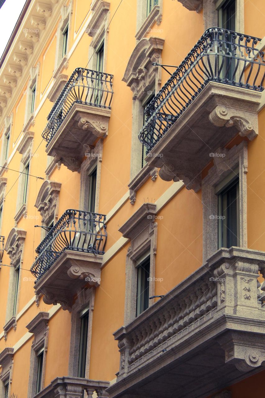 Side view of a yellow building with facade decorations and a metal fence.  Lugano,  Switzerland