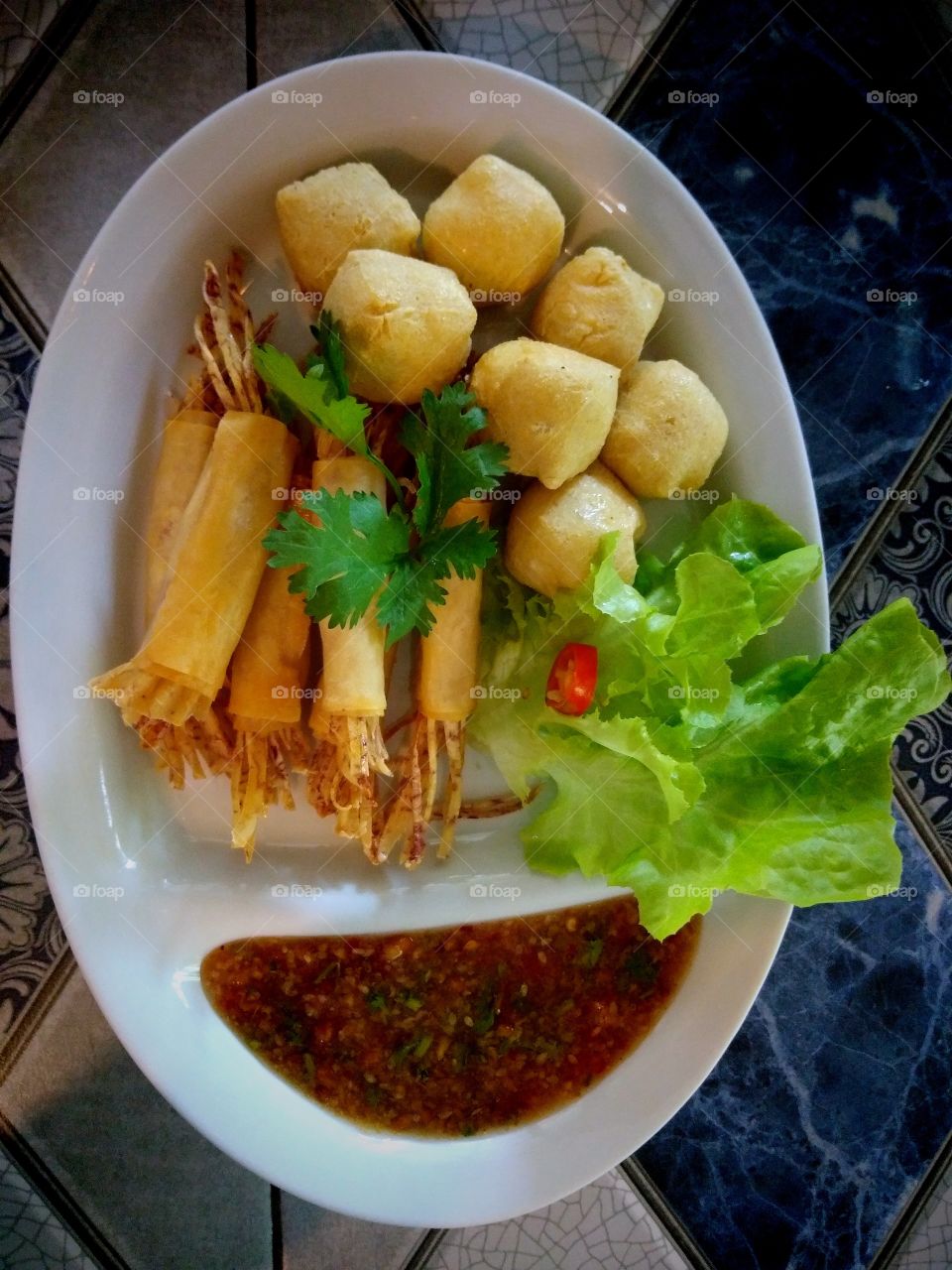 Thai appetizers , consisting of fried diced tofu and fried shredded taro served with sweet sauce and fresh vegetables.