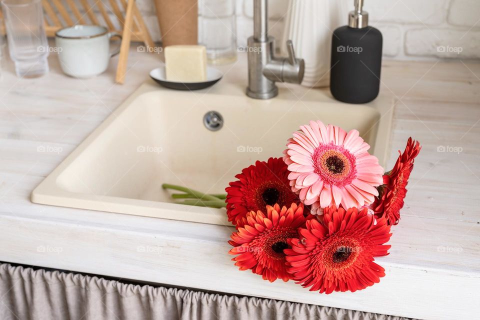 red gerbera flowers in sink