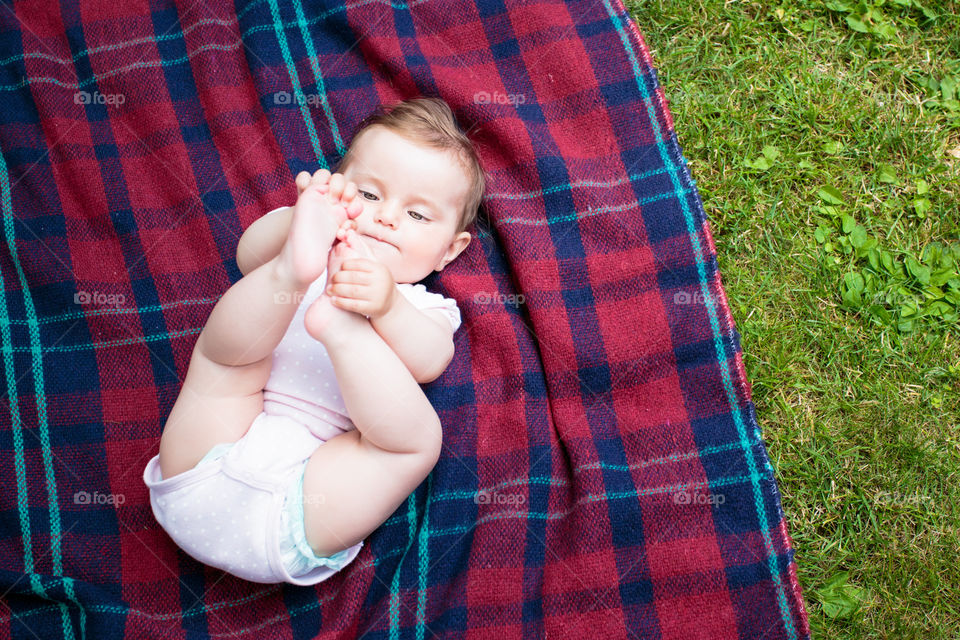 Baby in the garden. Baby lying on blanket in the garden