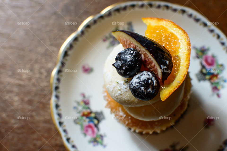 High angle view of fresh cream cupcake with sliced orange,  fig and blueberry garnish design 