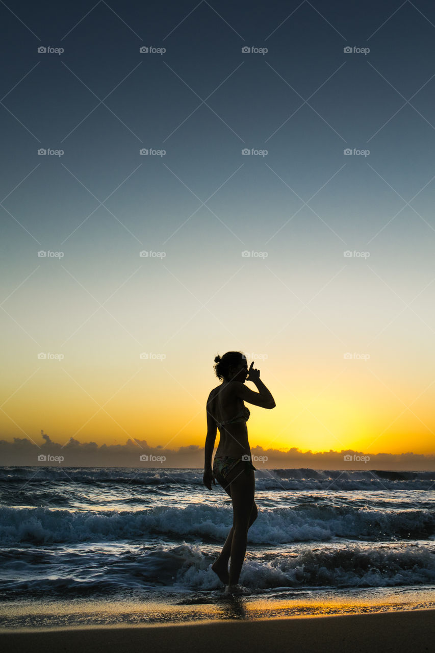 Woman in bikini drinking drink on beach in Jamaica in sunset
