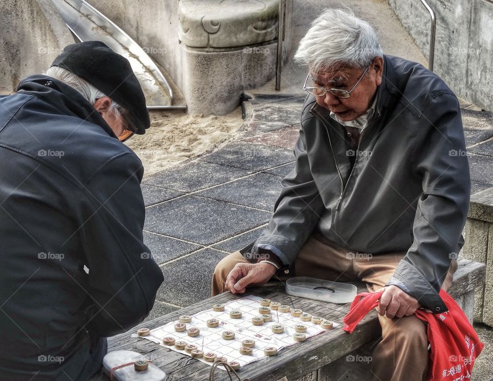 Elderly Chinese Men Playing Xiangqi Chinese Chess. Men Playing Chinese Chess In A Public Park