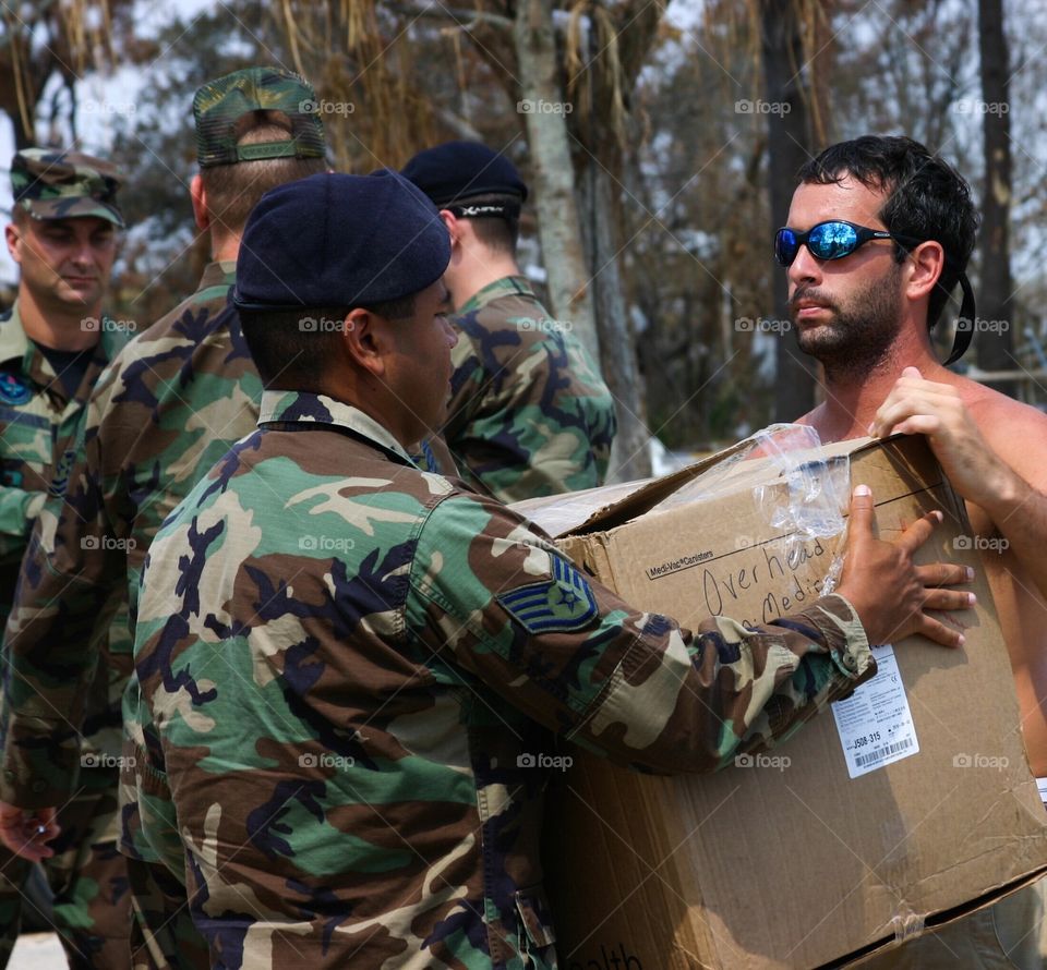 Air Force Staff Sergeant hands medical supplies to Hurricane Katrina survivor 