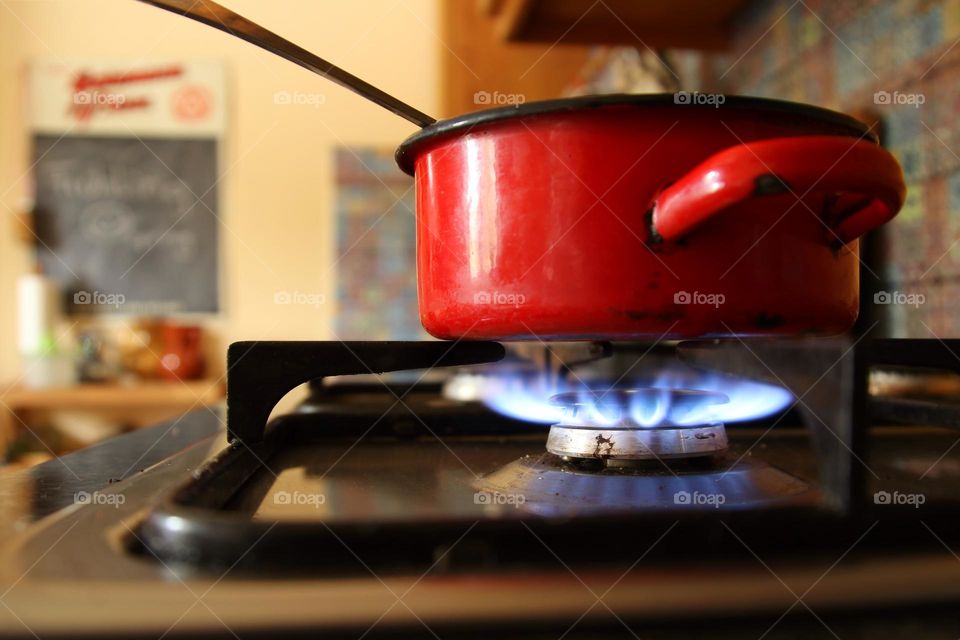 Close-up of a red saucepan standing on a gas burner in the kitchen