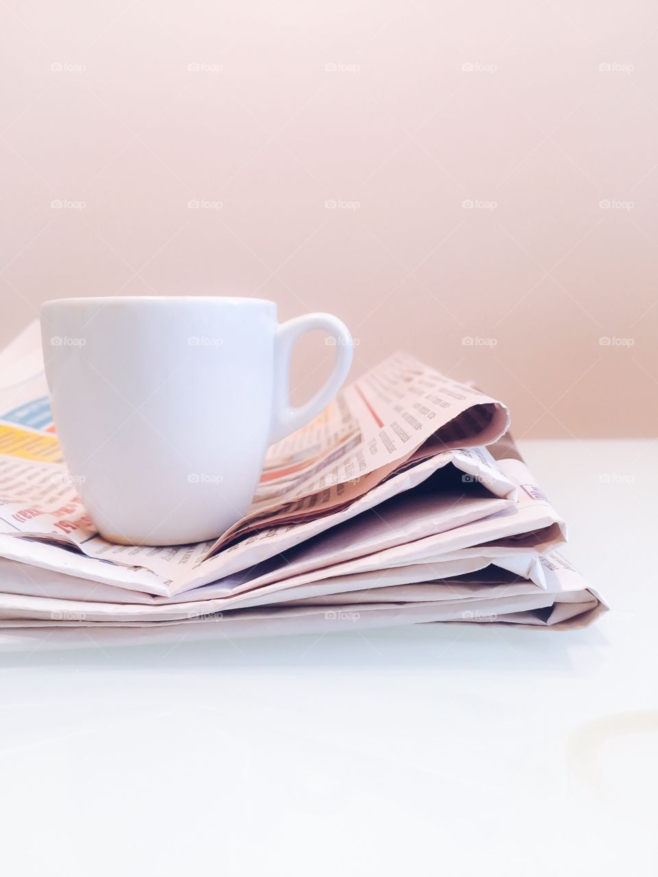 Read newspaper are stacked. And empty coffee cup on top