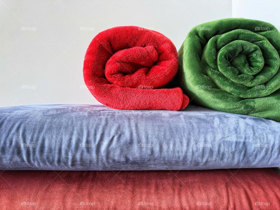 Rolled blankets and pillows in complementary colors