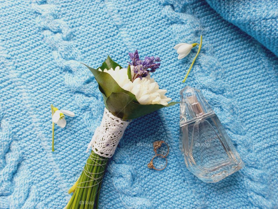 perfume and snowdrops on a blue sweater.