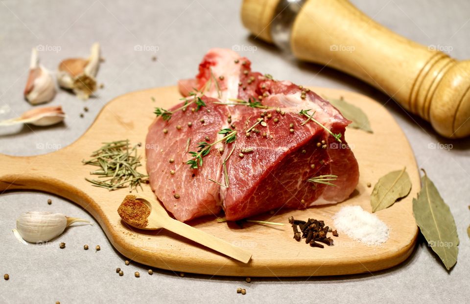 Raw meat on a wooden chopping board with spices