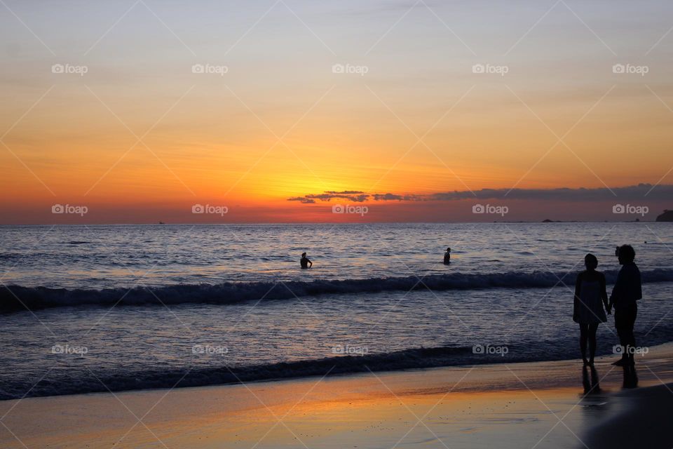 Magical sunset on the Pacific ocean.  The reflection of the sun on the sand and silhouette of bathers