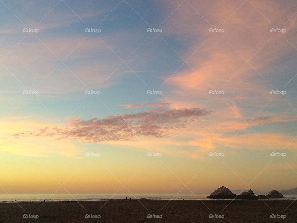 A person stands below the pastel sunset