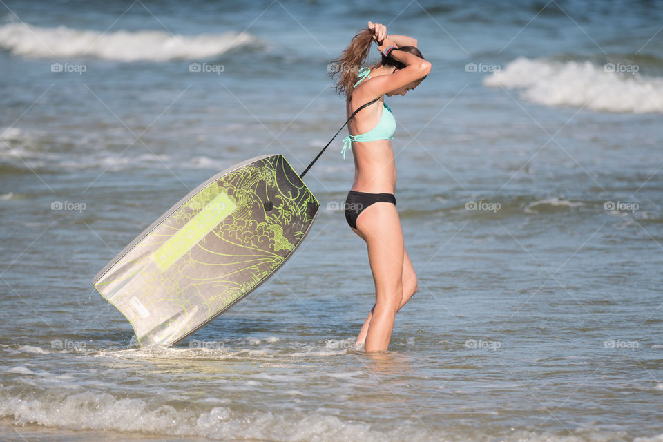 Girl tie her hair ready for the surf in the sea