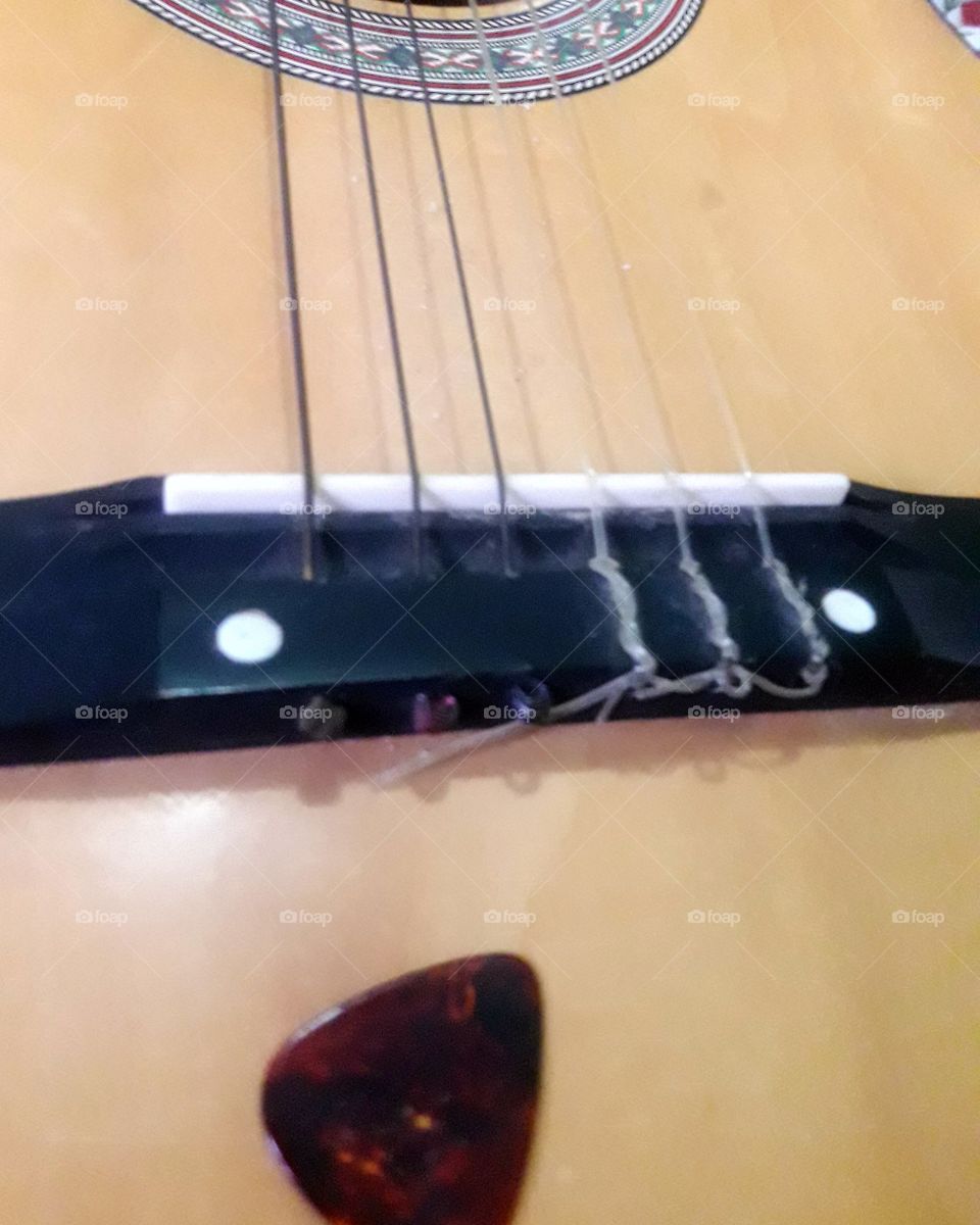 Foto de uma parte de um violão, instrumento de cordas muito usado por músicos.
