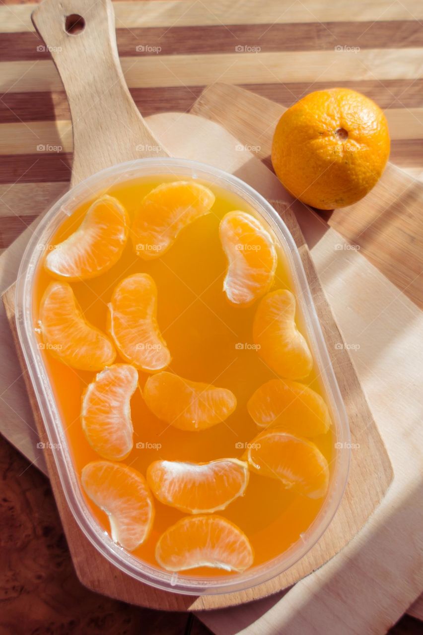 Delicious orange jelly with tangerine slices in a container and jelly worms.