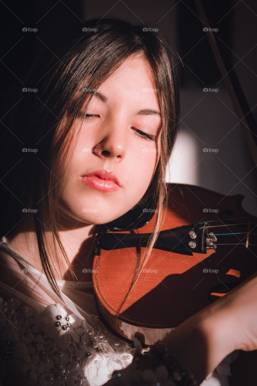 Girl holding a violin in the house