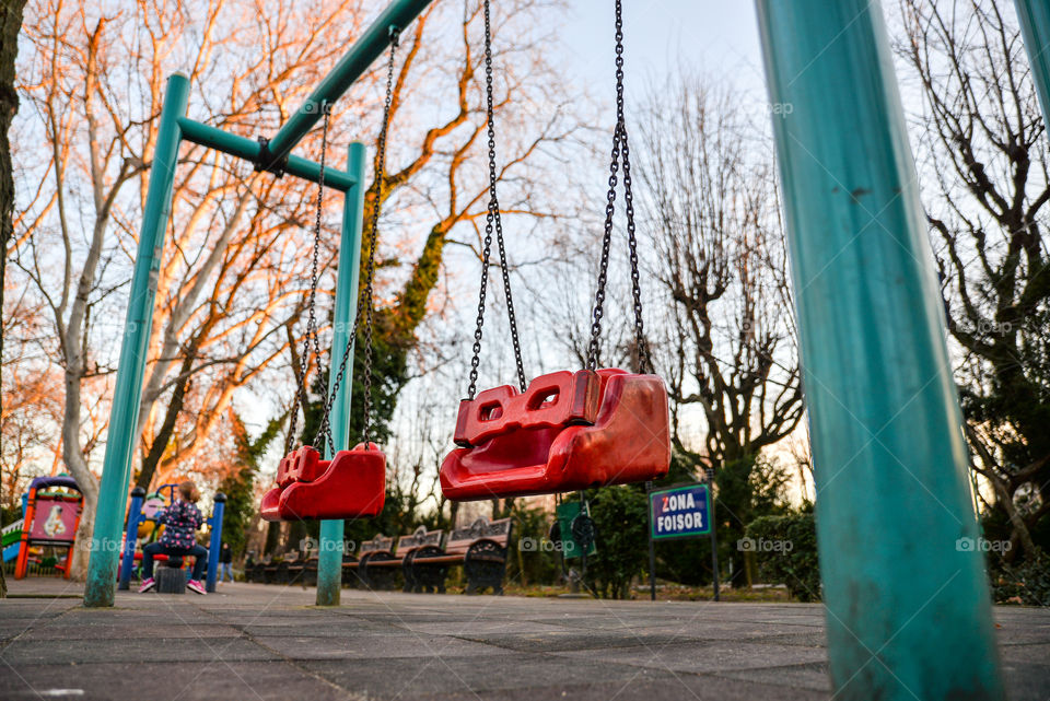 Set of red chain swings on modern kids playground