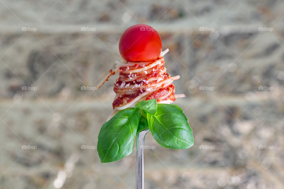 tomato, pasta and basil on a fork