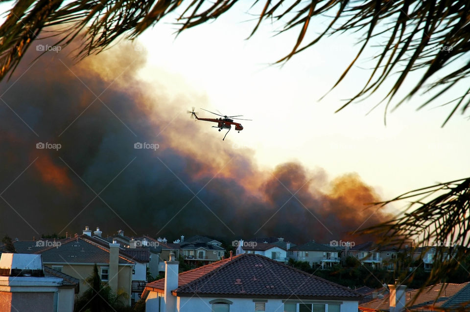 Water dropping helicopter attempts to contain a wild fire over a Housing development in Southern California. 