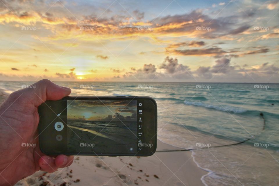 photographing sunrise with cellphone in the beach