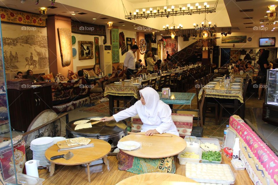 Istanbul is a vibrant city known for its art, history and culture. However, it can also be explored through its interesting local cafe, restaurant, cuisine and shop culture. This is a female cook/chef making bread in front of travelers and customers.