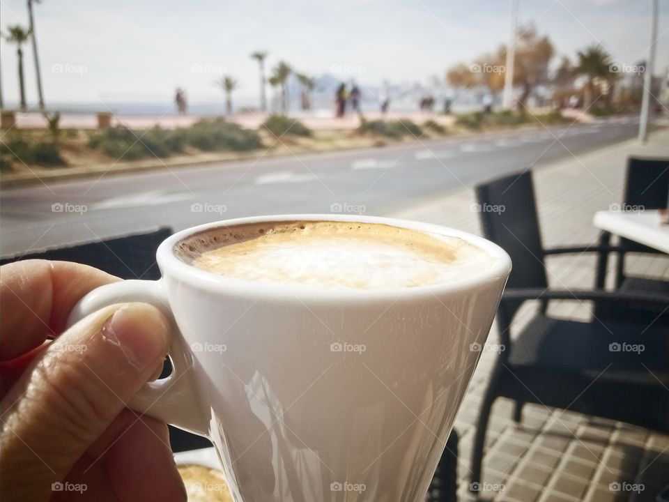 Savoring a delicious cup of coffee in the sun on a terrace next to the beach