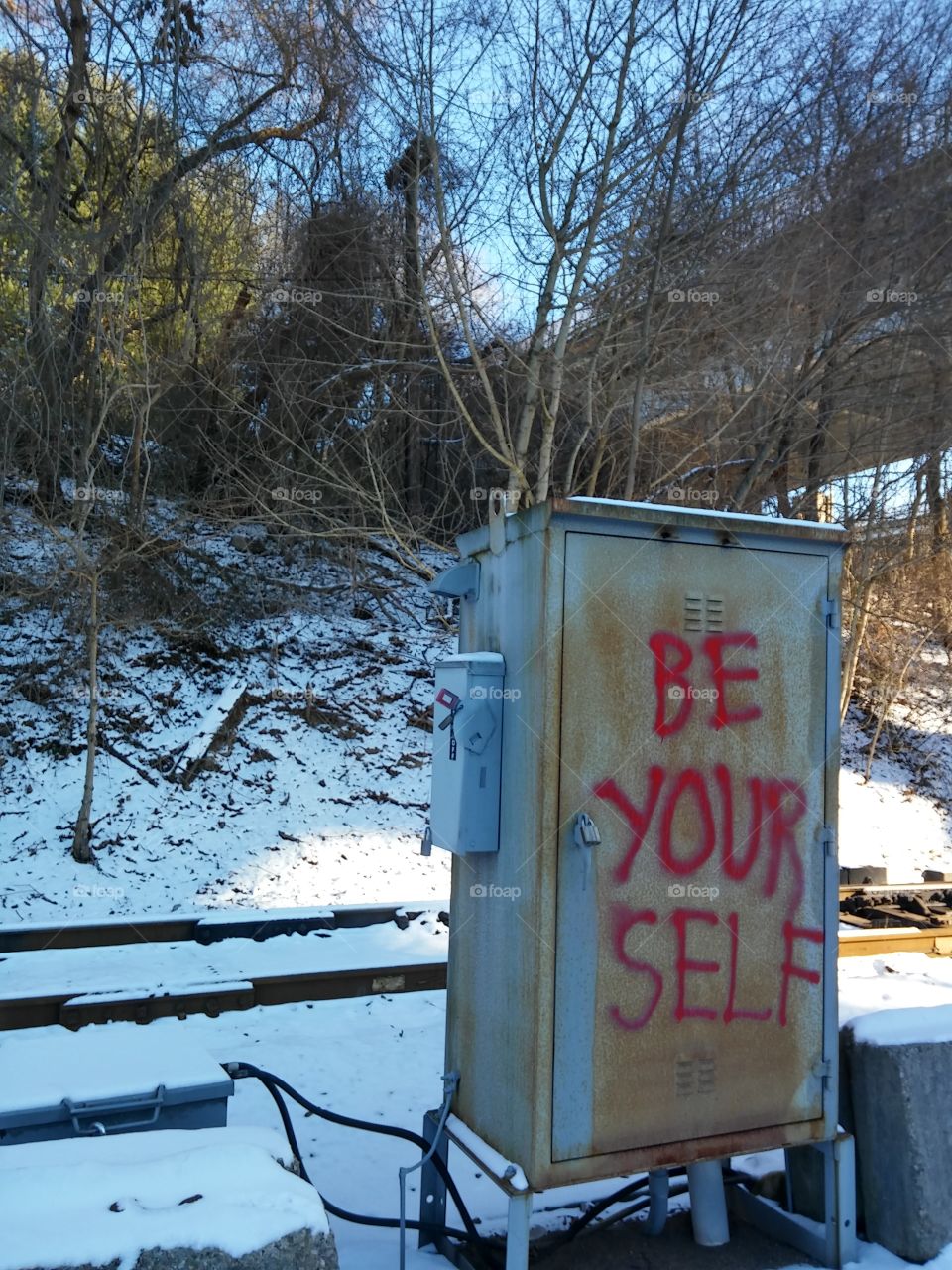 Inspirational graffiti sprayed on a switchbox aside train tracks, wintertime [original photo].
