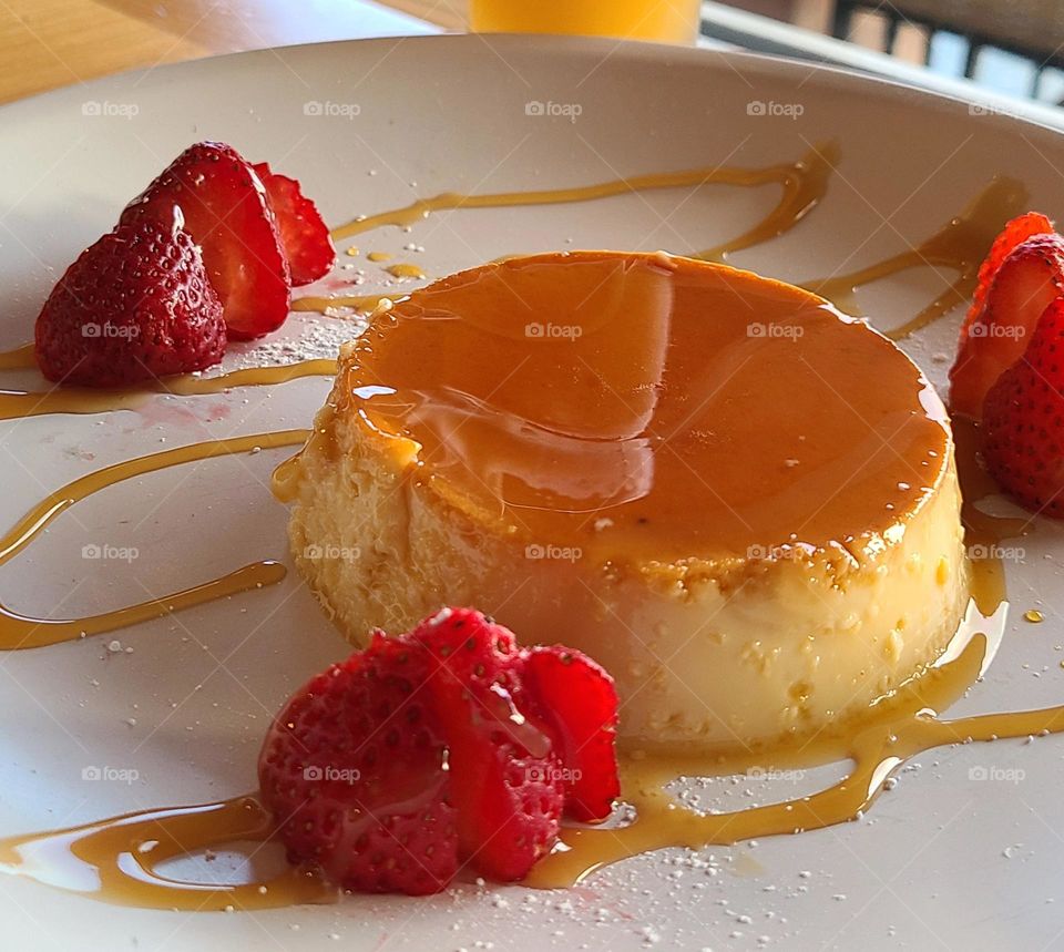 Beautiful plate of flan with caramel sauce on a white plate with delicious strawberries 