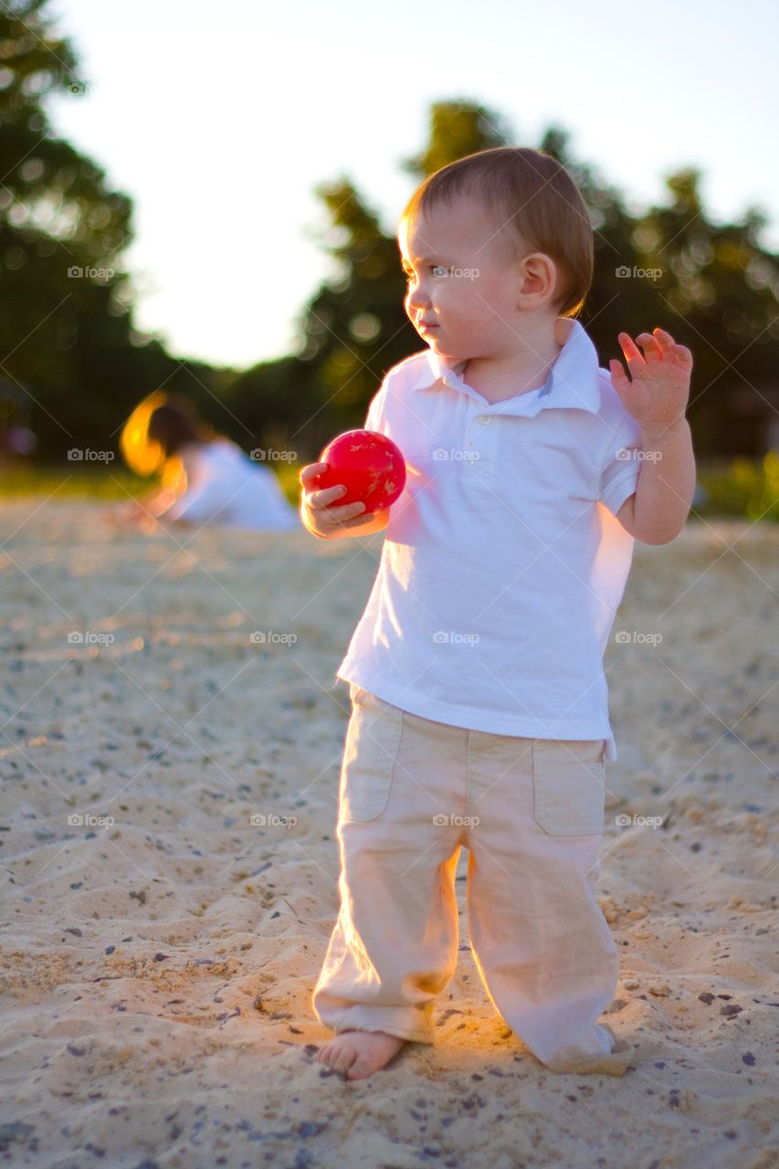 Cute boy holding ball in hand at beach