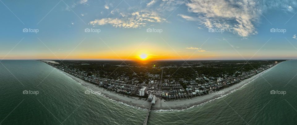 Wide angle drone photo of the sunsetting behind the beautiful beach in surfside South Carolina 