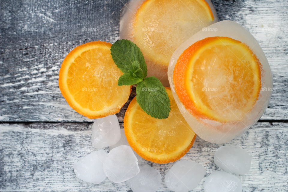 Oranges mint leaves and ice cubes on wood