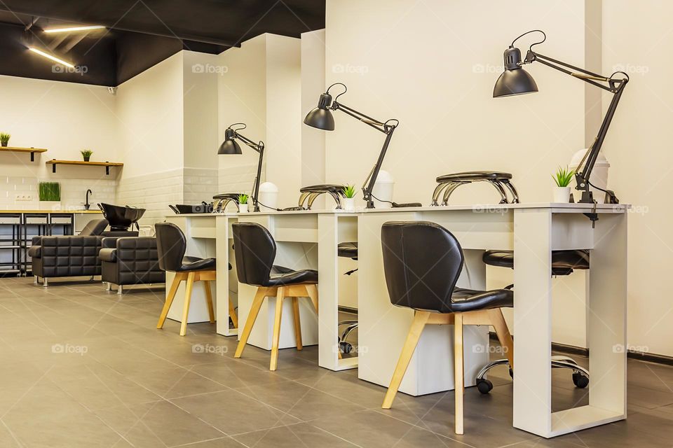 Interior of a modern beauty salon, manicure area. Manicure tables with lamps and cozy chairs in the barbershop. Concept of interior design for hairdressers and nail artists. Horizontal orientation