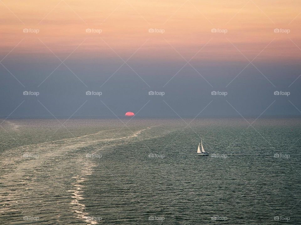 A sailboat on the open ocean at sunset 