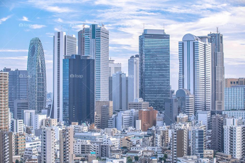 Shinjuku skyline seen on a beautiful day. Blue sky with clouds. This is one of the most crowded areas in Tokyo, Japan where many notable buildings call home.