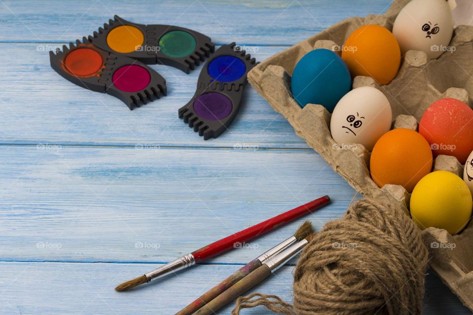 Painting Easter eggs on blue wooden table.  Easter decoration.