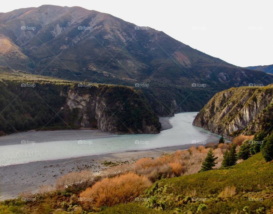 One of New Zealand’s many glacial rivers, an icy blue cutting through the red of the underbrush and verdant green cliffs.