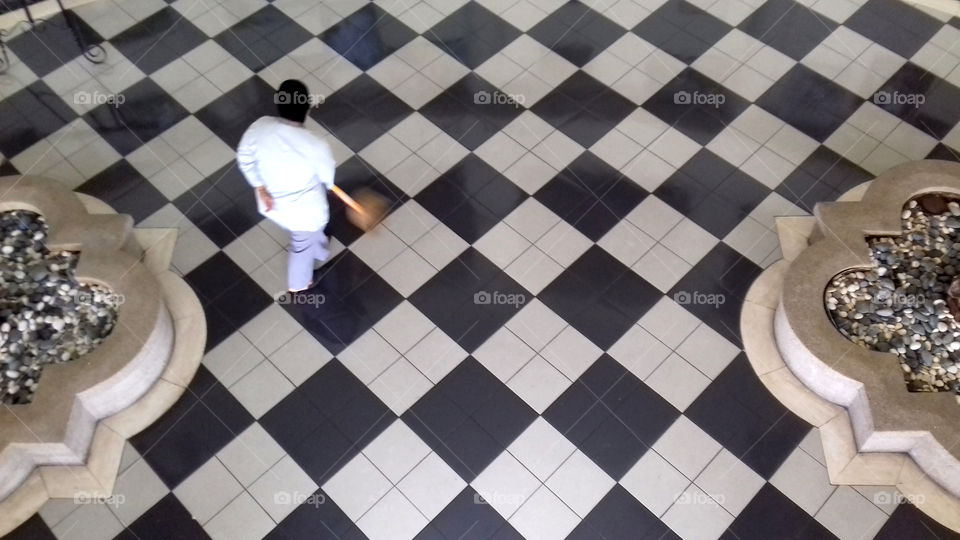 lady sweeping floor, black tiles first then the white ones