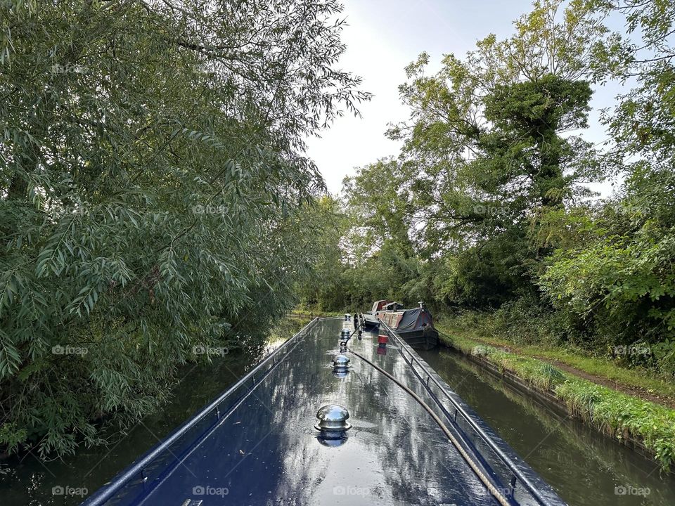 Early morning narrowboat cruise on Oxford canal in England near Rugby with trees reflection historic waterway 