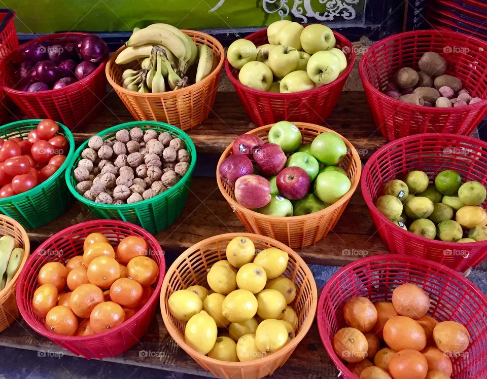 Colorful baskets fulls of different types of fruits displayed on shelves stand at the market 